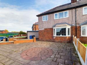 a brick house with a large patio in front of it at Stunning Family Home with Comfortable Surroundings in Wigan