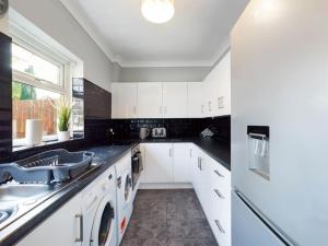 a kitchen with white cabinets and a sink at Stunning Family Home with Comfortable Surroundings in Wigan