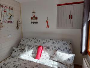 Cette chambre comprend un lit avec un oreiller rouge. dans l'établissement La Plagne Les Coches studio divisible ensoleillé, à La Plagne Tarentaise