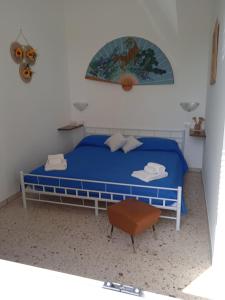 een slaapkamer met een blauw bed en een stoel bij E case tu Bertu in Marina di Mancaversa