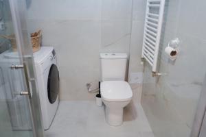 a white bathroom with a toilet and a washing machine at Sunlight Apartment in Skopje