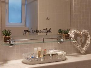 lavabo en el baño con espejo con un cartel que dice que eres hermosa en Gyógyvölgy apartman, en Egerszalók