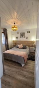 a bedroom with a large bed and a chandelier at LANA COTTAGE 3 Etoiles in Montjean +25 photos