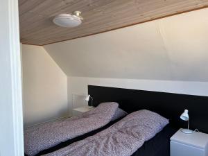 two beds in a bedroom with a black headboard at Hyggeligt byhus in Harboør