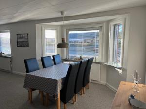 a dining room with a table and chairs and windows at Hyggeligt byhus in Harboør