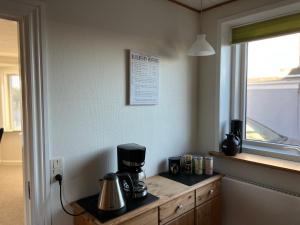 eine Kaffeemaschine auf einer Theke neben einem Fenster in der Unterkunft Hyggeligt byhus in Harboør