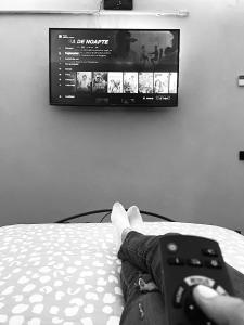 a person laying on a bed holding a video game controller at Relaxveld Galaxy in Curtea de Argeş