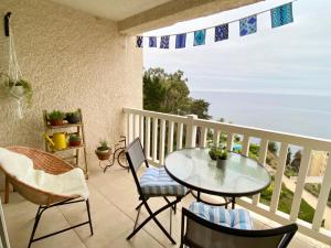 balcón con mesa, sillas y vistas al océano en Depto Frente al Mar con Piscinas, Quincho, Jacuzzi y Sauna, en Puchuncaví