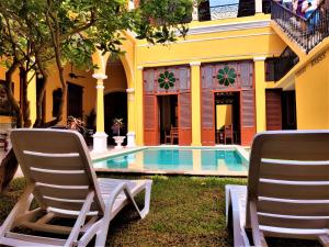 two chairs and a swimming pool in front of a house at Hotel Real Toledo by Kavia in Mérida