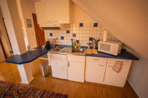 eine kleine Küche mit einer Spüle und einer Mikrowelle in der Unterkunft Gemütliches Apartment im wunderschönen Kallmünz in Kallmünz