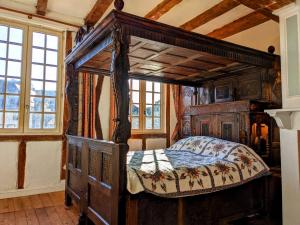 ein hölzernes Himmelbett in einem Zimmer mit Fenstern in der Unterkunft House of secrets in Morlaix