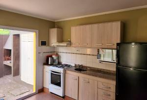 a kitchen with wooden cabinets and a black refrigerator at Apart Hotel Naga Huel in Sierra de la Ventana