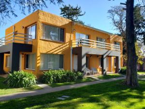 a yellow house with a tree in front of it at Apart Hotel Naga Huel in Sierra de la Ventana