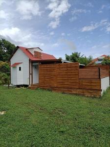 een huis met een houten hek in een tuin bij La tiny de titanse avec piscine in Cadet