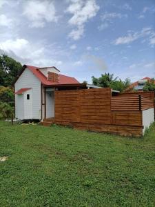 a house with a wooden fence in a yard at La tiny de titanse avec piscine in Cadet +2 photos