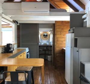 a kitchen with a wooden table and a refrigerator at La tiny de titanse avec piscine in Cadet