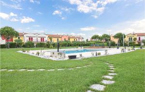 a backyard with a swimming pool and a grass field at Nice Apartment In Aprilia Marittima in Aprilia Marittima +8 photos