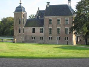 un grand bâtiment en briques avec une pelouse devant lui dans l'établissement Huize Ruurlo, à Ruurlo