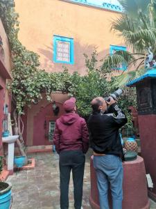 two people standing in front of a building with a telescope at Riad Dades Birds in Boumalne Dades