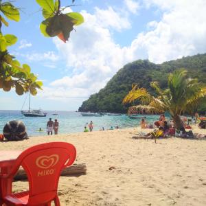 a beach with a red chair and people on the sand at Douceur Antilla apartment in Morne Blanc