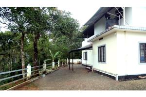 a white house with a fence next to it at Colonia Munnar Homestay in Munnar