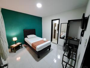 1 dormitorio con cama y pared verde en Hotel 9-25 en Pereira