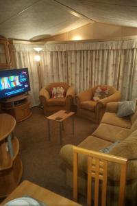 a living room with couches and a flat screen tv at 2 bedroom static caravan on quiet park near Caernarfon & Snowdonia in Caernarfon