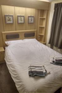 a bed with white sheets and towels on it at 2 bedroom static caravan on quiet park near Caernarfon & Snowdonia in Caernarfon