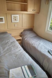 two beds in a small room with a window at 2 bedroom static caravan on quiet park near Caernarfon & Snowdonia in Caernarfon