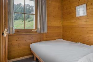 a bed in a wooden room with a window at Tschiffra EG in Bettmeralp