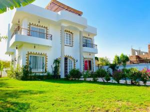 a white house with a lawn in front of it at Ali Luxury Villa in Luxor