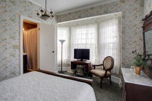 a bedroom with a bed and a television and a chair at Wilbraham Mansion in Cape May