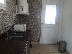 uma cozinha com um lavatório, uma janela e uma porta em Relax frente al Lago em Oliveros