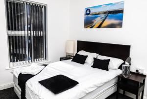 un letto bianco con cuscini neri in una stanza con finestre di Cozyhouses a Hull