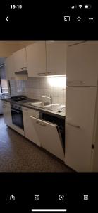 Una cocina con gabinetes blancos, un fregadero y una estufa. en Appartement Montreux, en Montreux