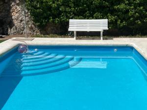 um banco sentado ao lado de uma piscina azul em Casa Rural Serafïn, Pet Friendly em Renera