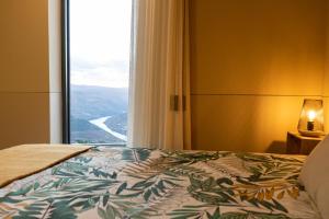 a bedroom with a bed and a large window at Dorigem Rooms in Casal de Loivos