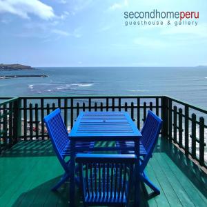 una mesa azul y sillas en una terraza con vistas al océano en Second Home Peru en Lima