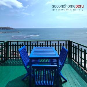 - une table bleue et des chaises sur une terrasse donnant sur l'océan dans l'établissement Second Home Peru, à Lima