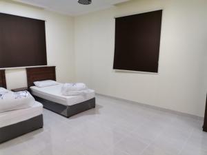 una camera con due letti e una parete nera di Al Basam Furnished Units a Yanbu