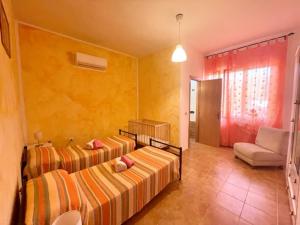 1 dormitorio con 2 camas, sofá y silla en Sa Covula, en Alghero
