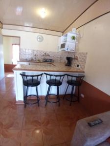 a kitchen with a counter and three bar stools at Casa entre la naturaleza in San Marcos