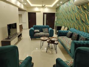 a living room with blue couches and a flat screen tv at Elysium Service Apartment in Islamabad