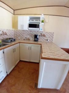 a kitchen with white cabinets and a microwave at Casa entre la naturaleza in San Marcos