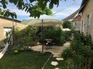 a patio with a table and an umbrella in a yard at Chez Fred avec vue sur le Château in Angles-sur-lʼAnglin