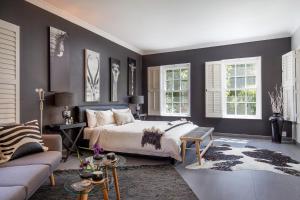 a bedroom with a bed and a couch and windows at 14 on Klein Constantia in Cape Town