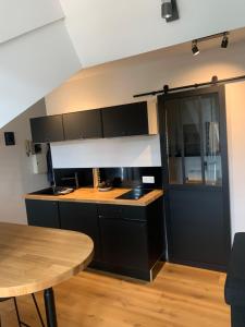 a kitchen with black cabinets and a wooden table at studio moderne in Barcelonnette