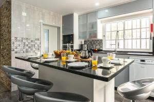 a kitchen with a black counter and chairs in it at Villa Salinas - Relax in the paradise surronded by nature and heated swimpool in Paul do Mar