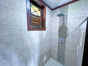 a bathroom with a shower with a window at Santosha Barbados in Saint Andrew