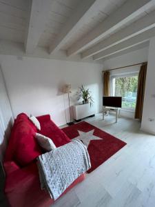 un soggiorno con divano rosso e tappeto rosso di Villa Natura appartamento Open Space con giardino a Trento